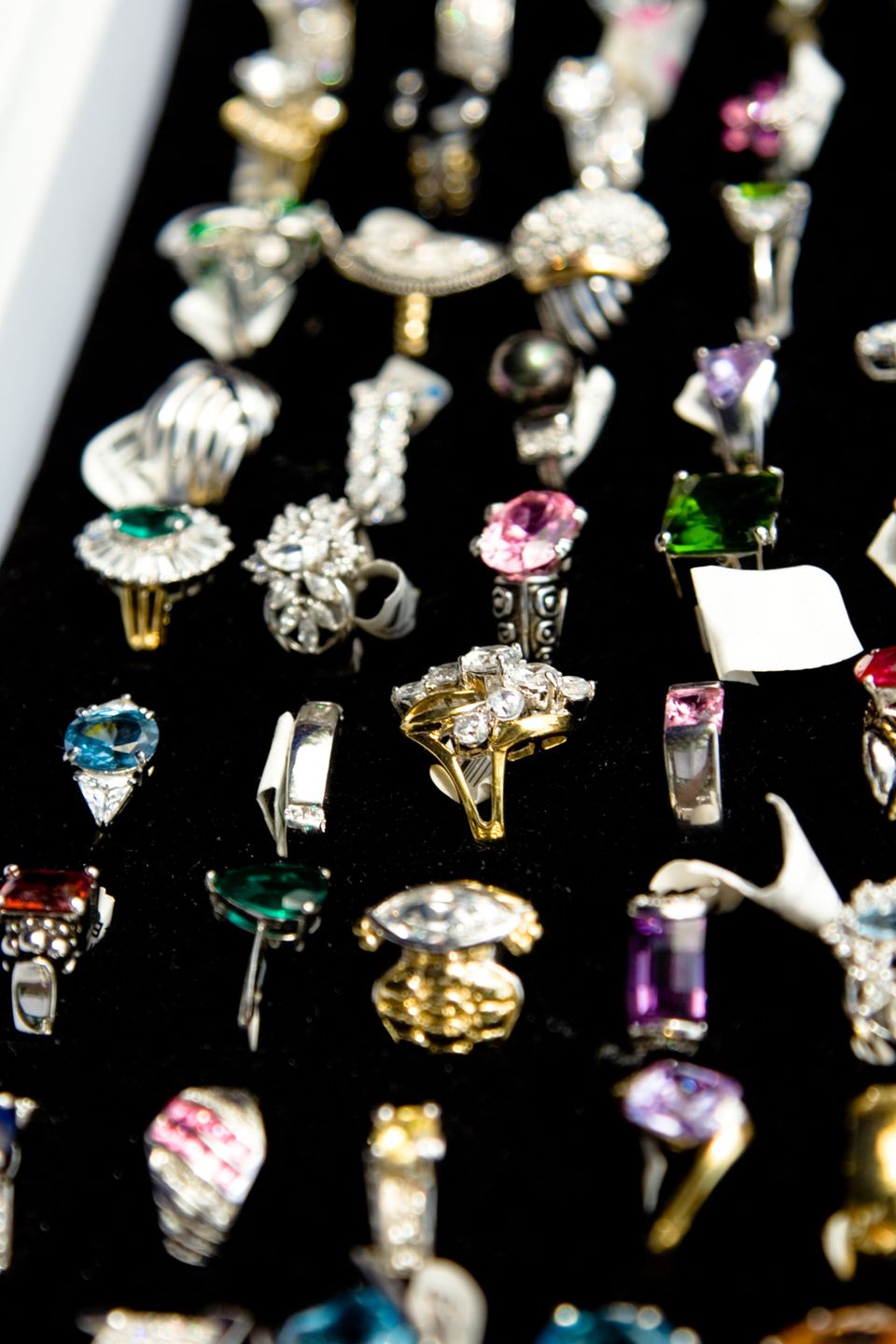 Auswahl gebrauchter Ringe mit farbigen Edelsteinen auf einem schwarzen Display