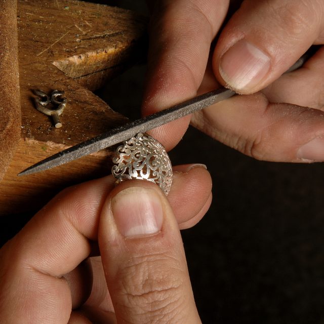 Goldschmied bearbeitet einen Ring mit einer Feile